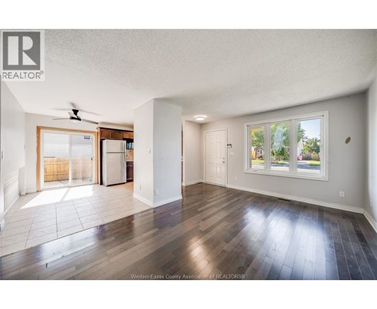 A spacious room with wooden floors and a ceiling fan.