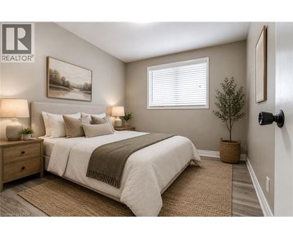 A well-lit bedroom with a large bed and a painting on the wall.