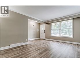 A spacious room with wooden flooring and a large window.