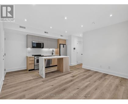 A modern kitchen with wooden floors and white walls.