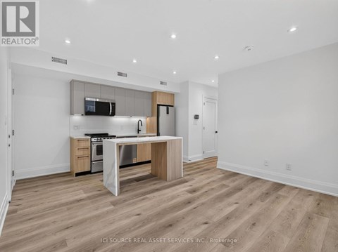 A modern kitchen with wooden floors and white walls.