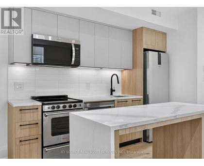 A modern kitchen with a stainless steel refrigerator, microwave, and oven.