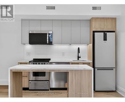 A modern kitchen with a stainless steel refrigerator and a wooden island.