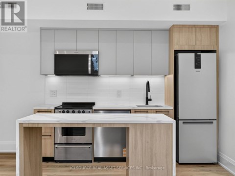 A modern kitchen with a stainless steel refrigerator and a wooden island.