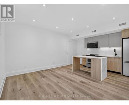 A modern kitchen with wooden flooring and white walls.