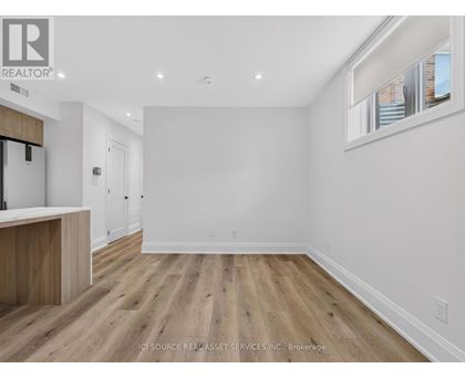 A spacious room with wooden flooring and white walls.