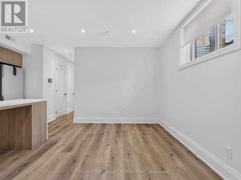 A spacious room with wooden flooring and white walls.
