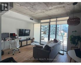 A living room with a couch, a chair, a television, and a window with a view of the city.