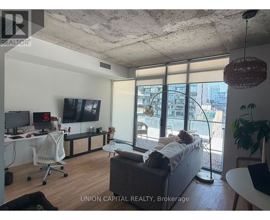 A living room with a couch, a chair, a television, and a window with a view of the city.
