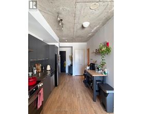 A kitchen with wooden floors and a concrete ceiling.