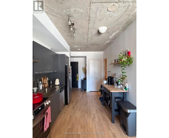 A kitchen with wooden floors and a concrete ceiling.
