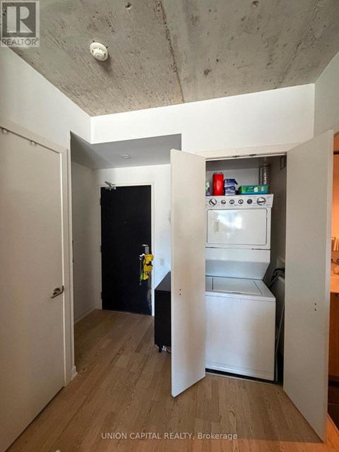 A small kitchen with a refrigerator and a black door.