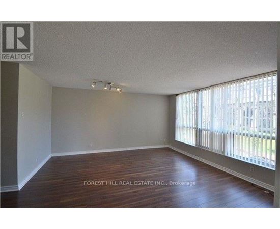 A room with wooden floors and a window with blinds.