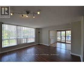 A spacious room with wooden floors and sliding glass doors leading to a backyard.
