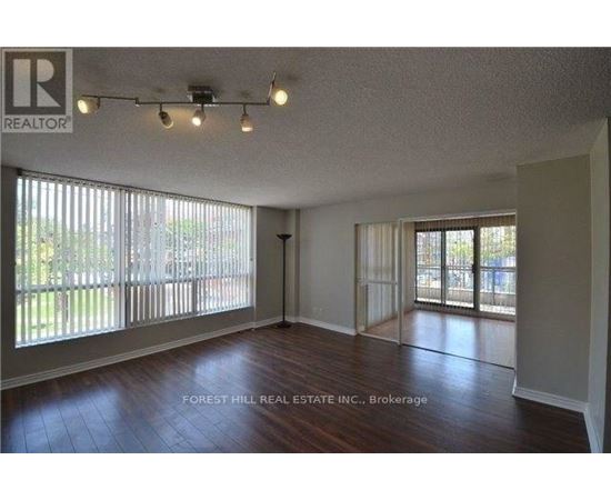 A spacious room with wooden floors and sliding glass doors leading to a backyard.
