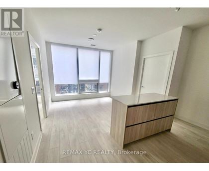 A spacious, well-lit room with a large window and a wooden cabinet.