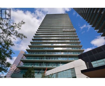 A tall building with many windows and balconies is seen from below.