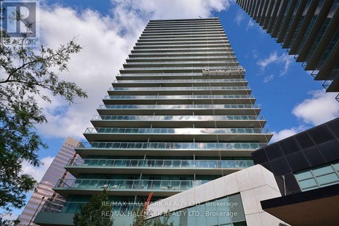 A tall building with many windows and balconies is seen from below.