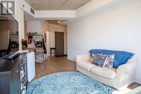 A living room with a couch and a kitchen area in the background.