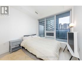 A bedroom with a large bed and a window overlooking a cityscape.