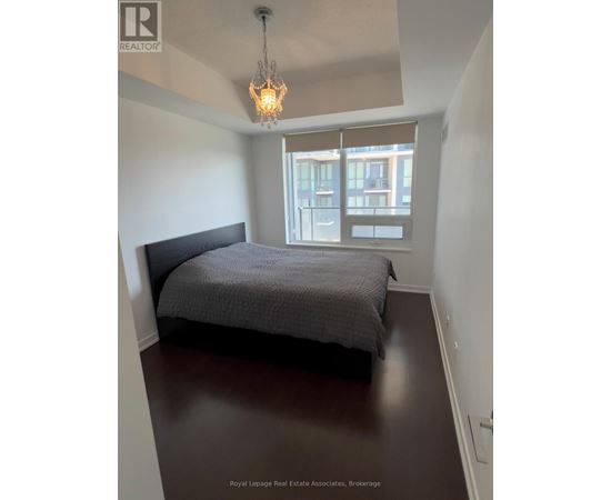A bedroom with a bed, a chandelier, and a window with blinds.