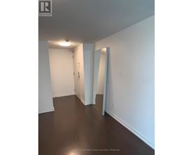 A white hallway with a door and a mirror on the wall.