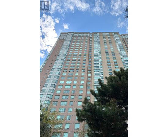 A tall building with many windows and a tree in front of it.