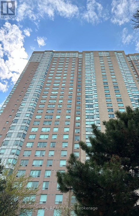 A tall building with many windows and a tree in front of it.