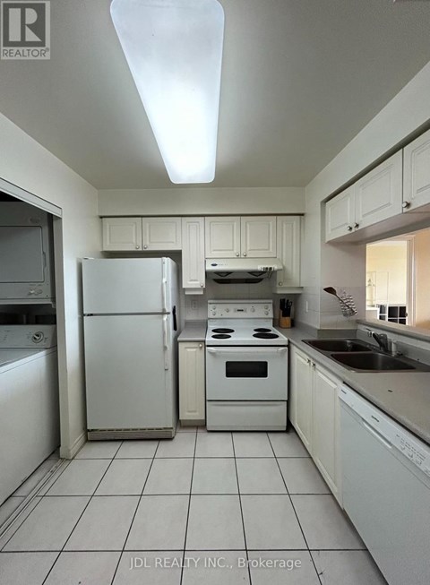 A white kitchen with a refrigerator, oven, and washing machine.