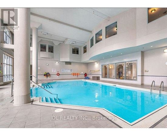 A large indoor swimming pool with a slide and a person sitting on the edge.