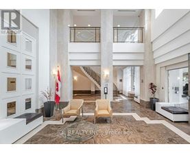 A spacious lobby with a staircase, chairs, and a reception desk.
