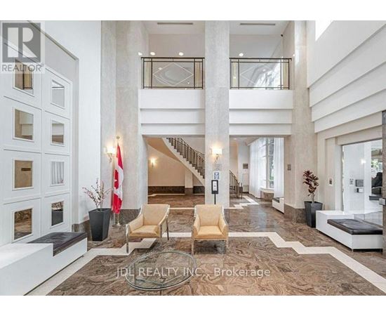 A spacious lobby with a staircase, chairs, and a reception desk.