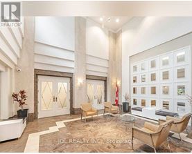 A spacious living room with a large window, a sofa, a chair, and a coffee table.