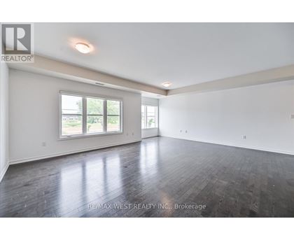 A spacious room with wooden floors and a large window.