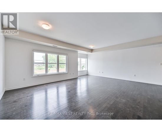A spacious room with wooden floors and a large window.
