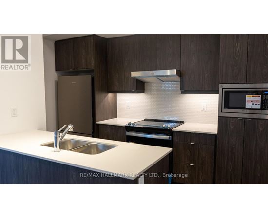 A modern kitchen with dark wood cabinets and stainless steel appliances.