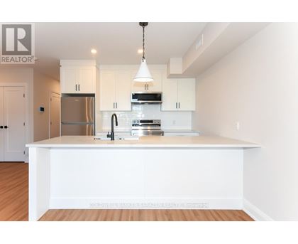 A modern kitchen with white cabinets and a wooden floor.