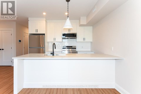 A modern kitchen with white cabinets and a wooden floor.