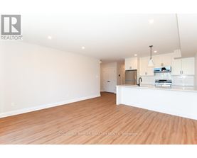 A spacious, empty room with wooden floors and white walls.