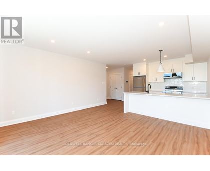 A spacious, empty room with wooden floors and white walls.