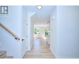 A hallway with a wooden staircase and a light on the ceiling.