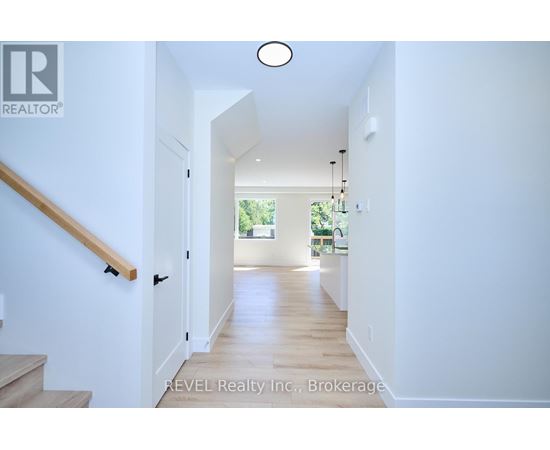 A hallway with a wooden staircase and a light on the ceiling.