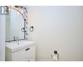A white bathroom sink under a mirror with a floral design.