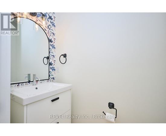 A white bathroom sink under a mirror with a floral design.