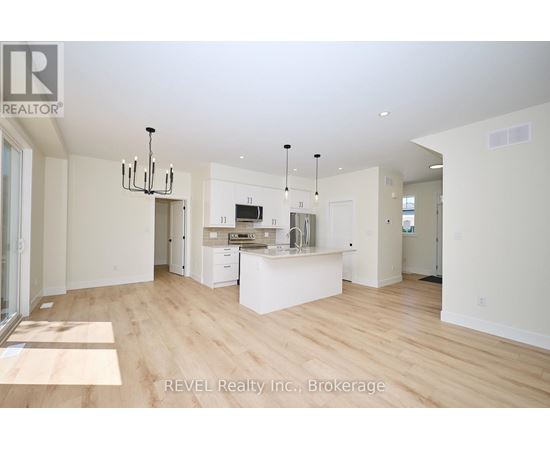 A spacious kitchen with white cabinets and a wooden floor.
