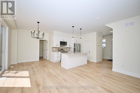 A spacious kitchen with white cabinets and a wooden floor.