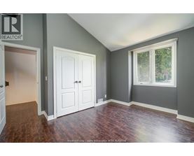A room with a wooden floor and a window with a view of trees.