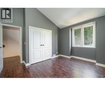 A room with a wooden floor and a window with a view of trees.