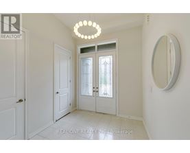 A white hallway with a chandelier and a mirror.