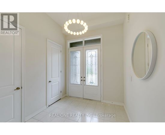 A white hallway with a chandelier and a mirror.